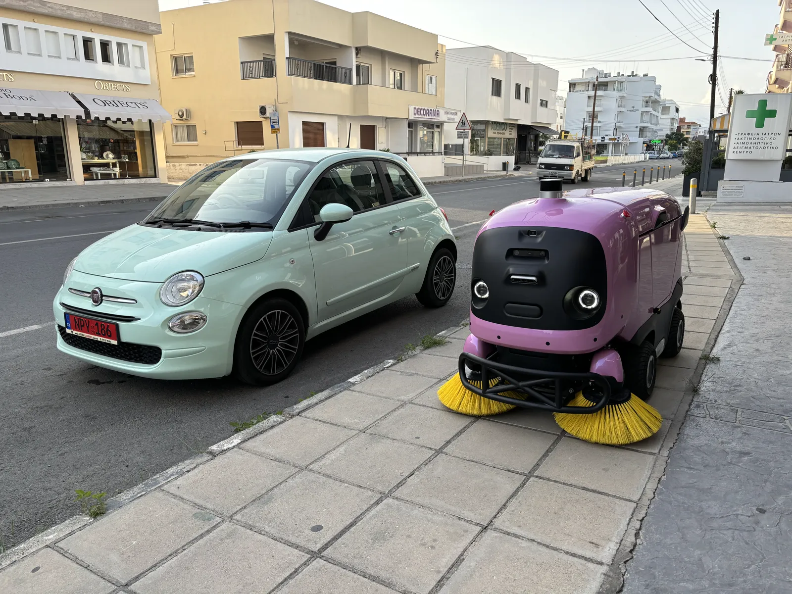 Αυτόνομο ρομπότ σκούπας σε δρόμο, δίπλα σε αυτοκίνητο